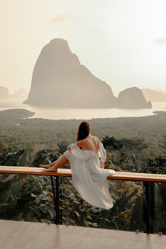 Woman with the white dress sit and see the mountain in early morning at the Sametnangshe Island viewpoint, Phang-Nga, Thailand.