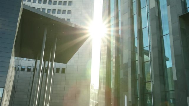 Smooth tracking shot of office building. Business building tracking shot. Beautiful sunny morning. Good for establishing shot, video opening or closing. Sunshine between two glass buildings. Prores