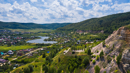 Fototapeta na wymiar Aerial view from the drone of the village on the background among the hills. The middle band of Russia.