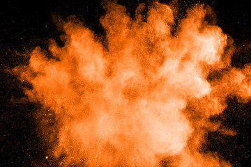 Abstract orange powder explosion on black background.Freeze motion of orange dust splash.