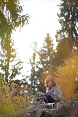 A beautiful brunette girl with curls, autumn in the Park by the water reading a book, clothes beige wool large knit, scarf warm, wind blowing, yellow foliage.