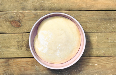 Dough in a pink bowl  on rustic rough wooden table, overhead top view, flat lay, closeup, copy space, homemade cooking and pastery concept