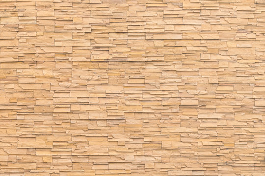Rock stone brick tile wall aged texture detailed pattern background in dark yellow cream  brown color