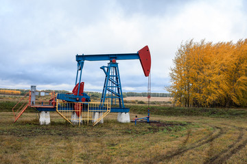 Fototapeta na wymiar Oil pump jack is on field at autumn season