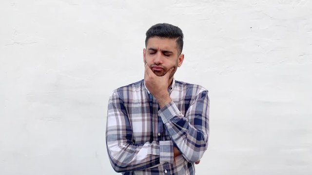 Portrait of confused handsome bearded man in blue checkered shirt standing scratching his head and looking away and thinking with puzzlement face. indoor studio shot isolated on white wall background.