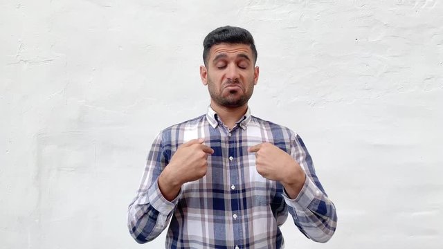 Portrait of proud handsome bearded man in blue checkered shirt standing, pointing and showing himself and looking with haughty confident face. indoor studio shot isolated on white wall background.