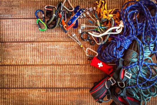 Climbing equipment for safe climbing sportsmen. Frame from safety equipment using in climbing, speleology, alpinism, over wooden background with copy space.