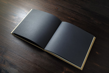 Blank black book mock up on wooden background. Template for placing your design.