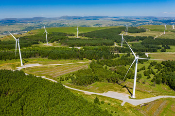 Aerial drone view of a large onshore windfarm on a green hillside