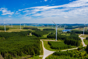 Aerial drone view of a large onshore windfarm on a green hillside