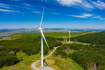 Aerial drone view of turbines at a large onshore windfarm on a green hillside (Pen y Cymoedd, Wales)