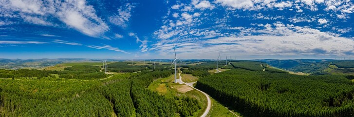 Aerial drone panorama of turbines at a large onshore windfarm in Wales, UK - obrazy, fototapety, plakaty