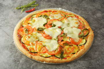 Vegetarian pizza made with wholegrain dough, with zuchinni, tomatoes and mozarella cheese. Healthy, dietical pizza. Top view.