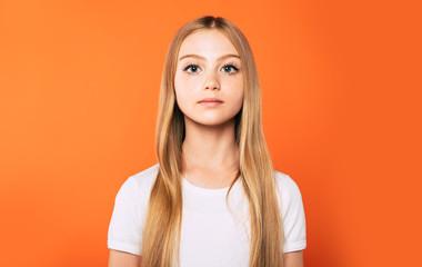 Calm portrait of beautiful little blonde girl in white t-shirt isolated on colorful background