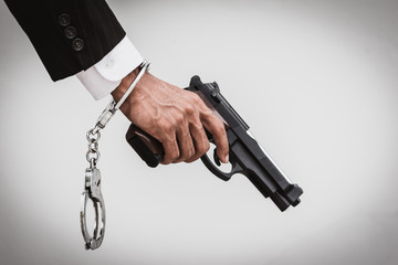 Close up of man in business suit holding a gun and shackle.