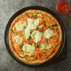 Vegetarian pizza made with wholegrain dough, with zuchinni, tomatoes and mozarella cheese. Healthy, dietical pizza. Top view.