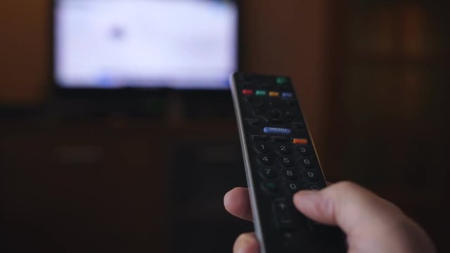 Close up shot of a elderly female hand holding the TV remote control and changing television channels.