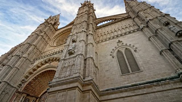 Majestic view of Palma Cathedral (Cathedral of St. Mary of Palma; La Seu) in Palma, Mallorca (Majorca), Spain. Shot from below against blue cloudy sky. Steadycam, UHD