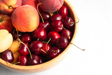 red and yellow cherry berries and peaches mixed at one plate, summer fresh healthy food, picture with space for text 