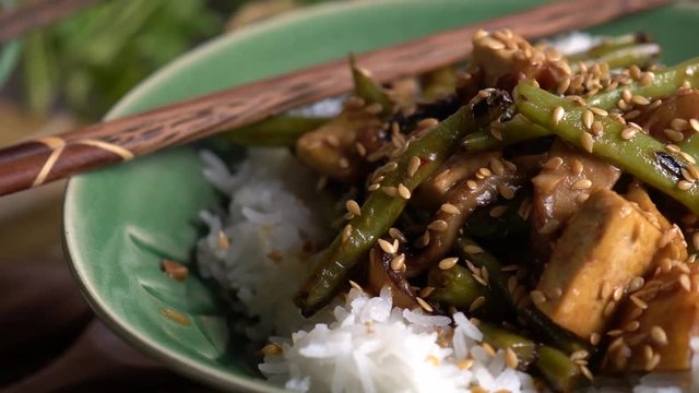 Extreme closeup dolly to the right of Szechuan green beans and tofu with sesame seeds.