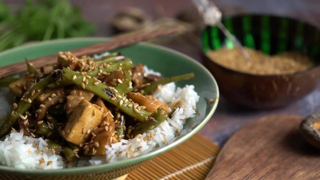 Extreme closeup dolly to the left of Szechuan green beans and tofu with sesame seeds.