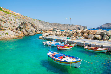 Fototapeta na wymiar Little port with colorful fishing boats and turquoise sea waters in Potamos village in Antikythera island in Greece