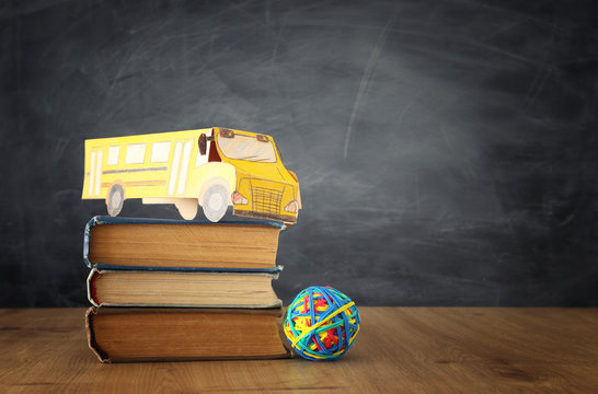 education and back to school concept. cardboard bus and books in front of classroom blackboard