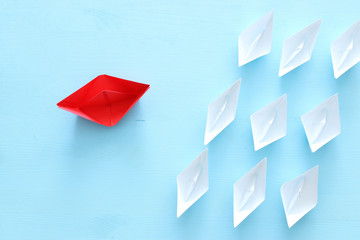 business. Leadership concept image with paper boats on blue wooden background. One leader guiding others.