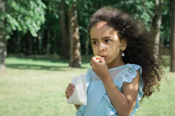 Fototapeta premium Little beautiful girl eats fried potatoes with fast food