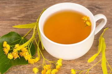 linden summer tea in white cup on wooden table, healthy and tasty hot drink