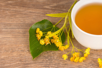 linden summer tea in white cup on wooden table, healthy and tasty hot drink