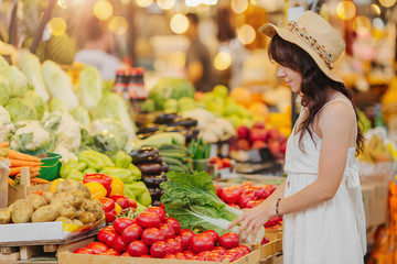 Woman is chooses  fruits and vegetables at food market. Reusable eco bag for shopping. Zero waste...