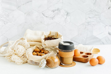 Nuts, dried fruits and  groats  in eco cotton bags and glass jars on white table in the kitchen. Zero Waste Food Shopping.  Waste-free living