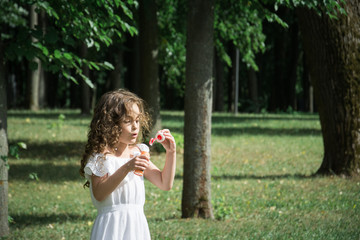 Cute little girl is blowing a soap bubbles