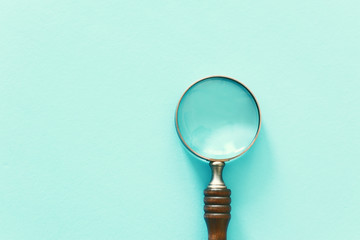 vintage magnifying mlass with wooden handle over blue background. top view, flat lay
