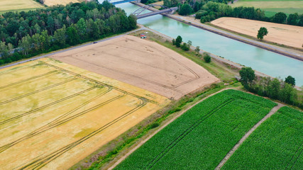 Aerial view of a canal that runs through fields, meadows and arable land in the flat landscape of northern Germany.