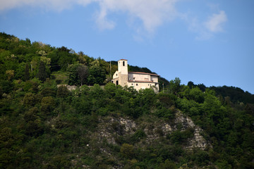 Fototapeta na wymiar An ancient church among the vegetation on the slopes of a hill