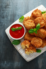 Fried Mac, macaroni and Cheese Bites in breadcrumbs with ketchup sauce on white wooden board