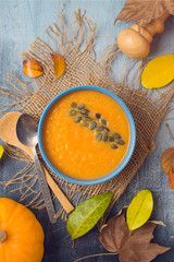 Pumpkin soup on rustic background. Autumn concept with pumpkin and fall leaves.