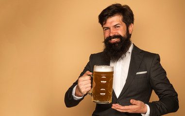 Hipster in black suit relaxing at pub. Emotional funny bearded drunk hipster holds craft bottled beer. Handsome barman holding a pint of beer.