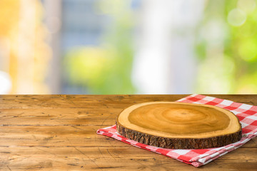 Empty wooden table with tablecloth and wooden board over abstract background
