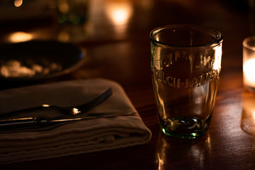 Dark French Bistro Restaurant In Newport, Rhode Island Wooden Table With Candles, Glasses and Place Settings.