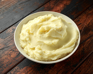 Mashed potatoes in white bowl on wooden rustic table. Healthy food