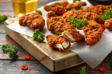 Breaded chicken strips with beer, ketchup and mayonnaise on wooden board