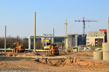 Heavy construction equipment and earthmoving excavators working on a construction site in the city. Laying or replacement of underground storm sewer pipes.