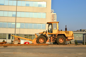 Front-end loader working on construction site during the renovation of the road. Laying or replacement of underground storm sewer pipes. Installation of water main, sanitary sewer, storm drain systems