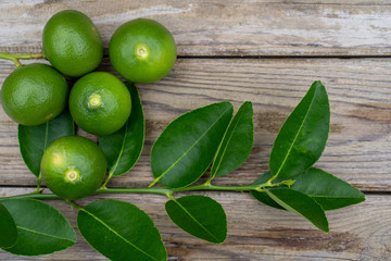 Fresh limes or green lemons on wood table background. Top view with copy space