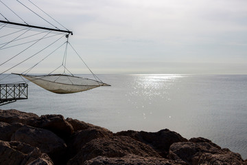 Shore-operated lift net at the Port of Senigallia, Province of Ancona, Marche, Italy, glittering Adriatic Sea water surface in te background, Chinese fishing net