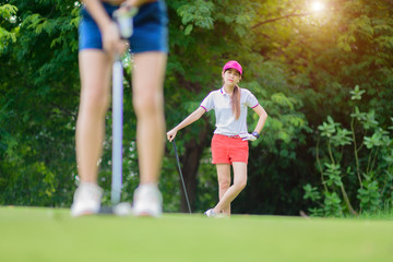 boring of young woman golfer or competitor or golf mate waiting for another dawdle golfer putting...