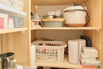 Wooden shelves with food and utensils, kitchen appliances in the pantry